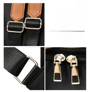 Close-up of polished gold-tone metal hardware and brown leather trim on a canvas backpack
