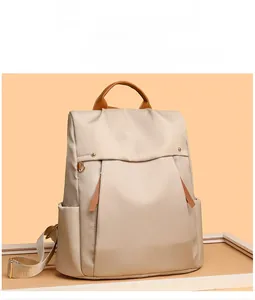 Close-up of khaki canvas backpack featuring premium brown leather handles and side pockets