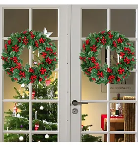 Detail von weihnachtlichen Kränzen mit roten Beeren und grünen Blättern an einer Tür