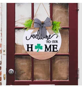 Close-up of wooden welcome door sign with burlap bow and green shamrock detail