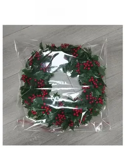 Weihnachtskranz-Verpackung mit künstlichen grünen Blättern und roten Beeren im Beutel