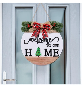 Detail of wooden welcome sign with plaid bow and festive pine needles on a blue door