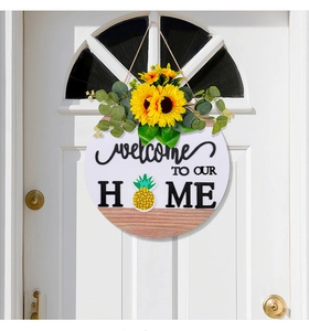 Detail of round wooden welcome sign featuring sunflower decor and pineapple letter O art