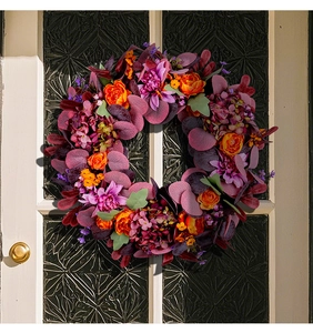 Détail d'une couronne d'automne avec roses orange et eucalyptus sur porte blanche