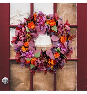 Détail d'une couronne d'automne avec fleurs violettes sur une porte rouge rustique