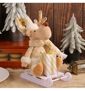 Close-up of reindeer plush with gold antlers on white sled base with gift box