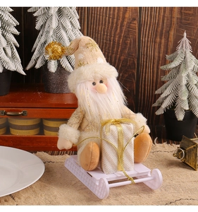 Detail of Santa plush doll in beige robe with star sequins sitting on white sleigh decor
