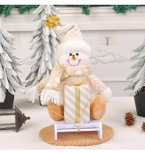 Detail view of a plush Christmas snowman doll holding a gift on white plastic sled runners