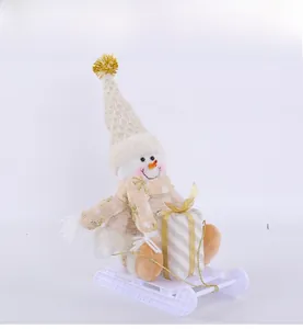 Detail of Christmas snowman figurine with beige knitted hat and gift on white sleigh