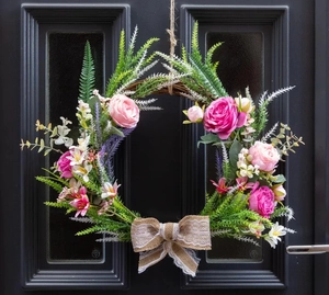 Detail of faux roses and lavender on a grapevine wreath with a rustic lace burlap bow
