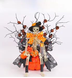 Detail of Halloween skeleton sitting on an orange pumpkin with black glittery branches