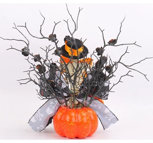 Detail of Halloween ornament with pumpkin base, black hat, and skeletal dry branches