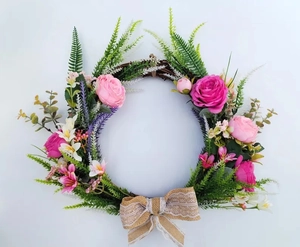 Detail of pink roses and faux fern on a rustic grapevine wreath with a burlap lace bow