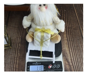 Detail of plush Santa Claus on a white sleigh being weighed on a digital scale