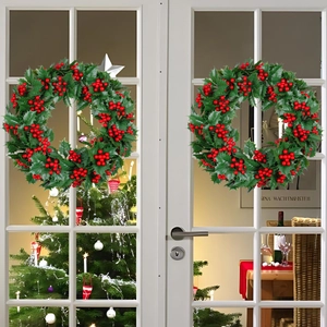 Zweiteiliges Set Weihnachts-Kränze mit grünen Blättern und roten Beeren an einer Tür