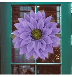 Macro detail of purple burlap sunflower wreath with textured center on a vintage door