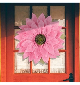 Close-up of pink burlap sunflower wreath with woven mesh texture on a wooden door