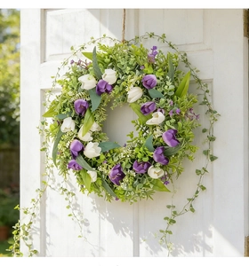 Detalle de corona de tulipanes artificiales con flores moradas y blancas en puerta blanca