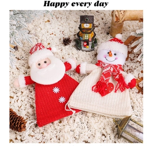 Detail of knitted Christmas gift bags with Santa and snowman motifs on faux snow