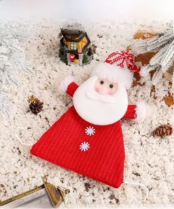Detail of knitted Santa Claus gift bag with white beard and snowflake button on snow