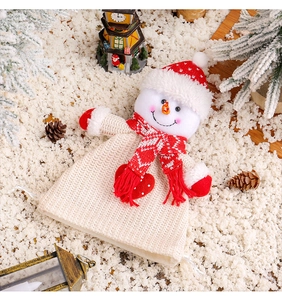 Detailed knit snowman gift bag with red scarf and hat among festive Christmas decor