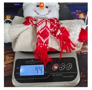 Detailed view of handmade knitted snowman Christmas gift bag on a digital scale weighing 44g