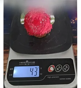 Détail macro d'une figurine de sapin de Noël en peluche rouge pesée sur une balance