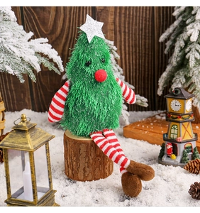 Detail of cute green plush Christmas tree doll with long legs on a rustic wooden stump