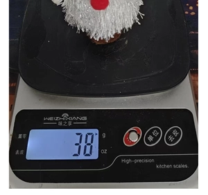 Vue macro d'un gnome de Noël en peluche pesant 38g sur une balance pour l'affichage du poids