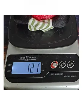 Close-up detail of a plush Christmas tree doll showing weight of 121g on a scale