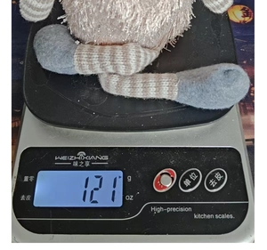 Detailed view of pink plush Christmas tree doll with striped long legs on weighing scale