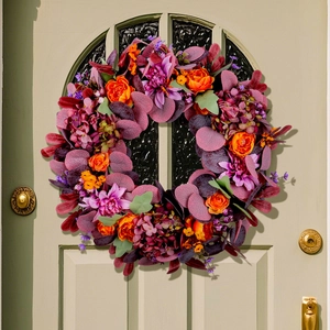 Couronne de fleurs d'automne avec dahlias mauves et roses oranges sur une porte vintage