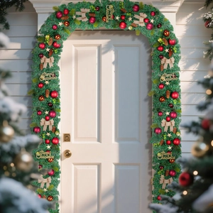 Guirlande de Noël avec pommes de pin, nœuds et boules sur une porte blanche