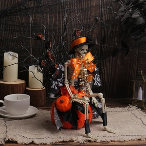 Skeleton figurine with mini top hat sitting on an orange pumpkin for Halloween decor