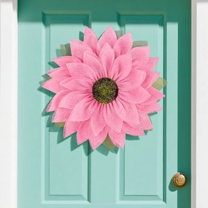 Pink burlap sunflower wreath with black center on a blue wooden door for home decor