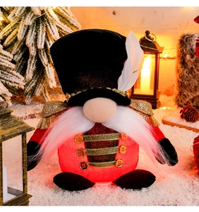 Detail of a glowing Christmas nutcracker gnome with red knit fabric and a feather hat