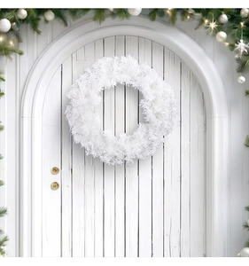 Detalle de una corona de Navidad artificial blanca colgada en una puerta de madera blanca