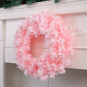 Corona de Navidad rosa con agujas nevadas en una repisa de chimenea blanca elegante