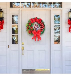 Detailed Christmas wreath featuring red velvet bow berries and nativity scene on a white door