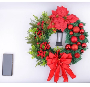 Close-up of Christmas wreath with red poinsettia, berries, pine cones and mini lantern