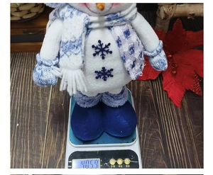 Detail shot of a plush Christmas snowman decoration weighing 405.9g on a digital scale