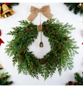 Detail of Christmas wreath with pine cones, a burlap bow and a vintage brass bell