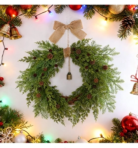 Close-up of a Christmas wreath with pine cones, burlap bow, and a vintage bronze bell