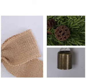 Macro detail of Christmas pine needles with vintage bronze bell and burlap ribbon decor