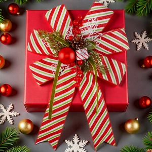 Scatola regalo di Natale rossa con fiocco a righe, pigne e decorazioni festive su grigio