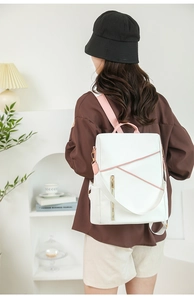 Detail of pink geometric pattern and side zipper on a white leather fashion backpack