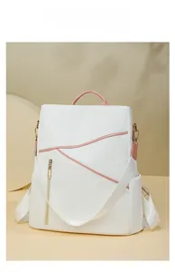 Detail view of pink leather accents and gold zippers on the white minimalist backpack