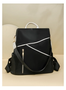 Detail view of water-resistant black nylon backpack with stylish white trim and gold zipper
