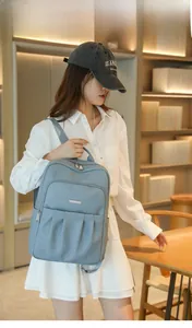Detail of grey-blue leather backpack with litchi texture and multiple zipper pockets
