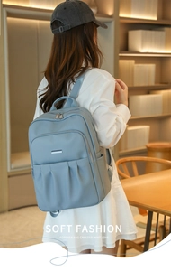 Detail showing the light blue Oxford backpack with front zipper and accordion fold design